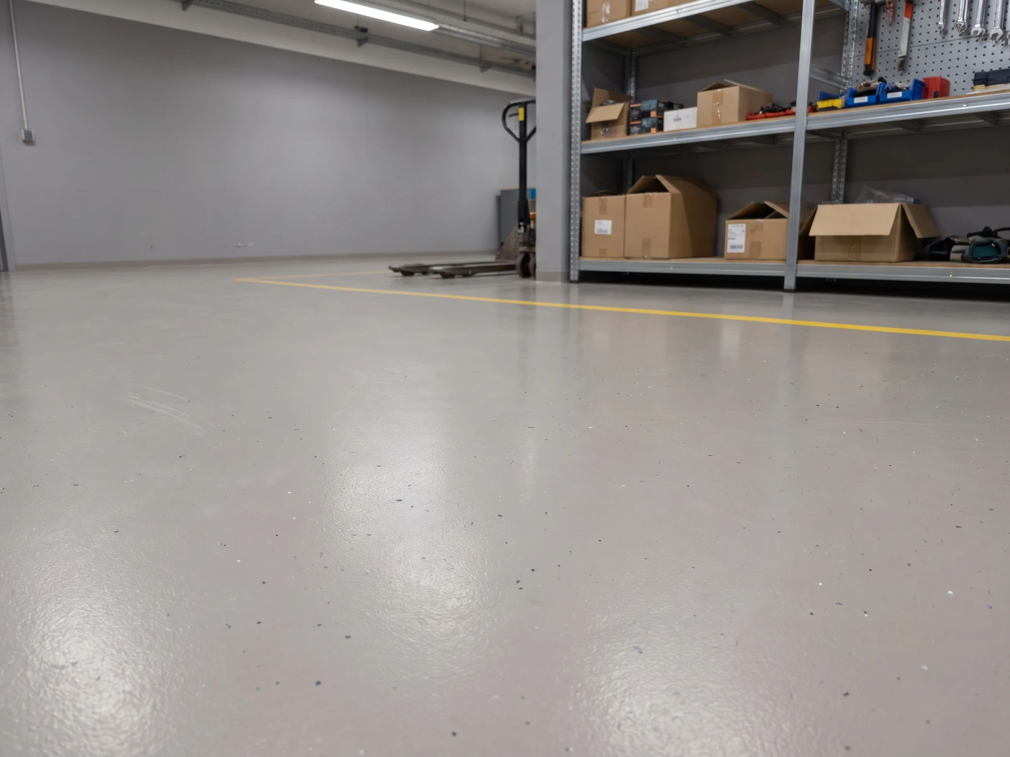 Werkstatthalle mit grauem Epoxidharzboden und gelber Markierung